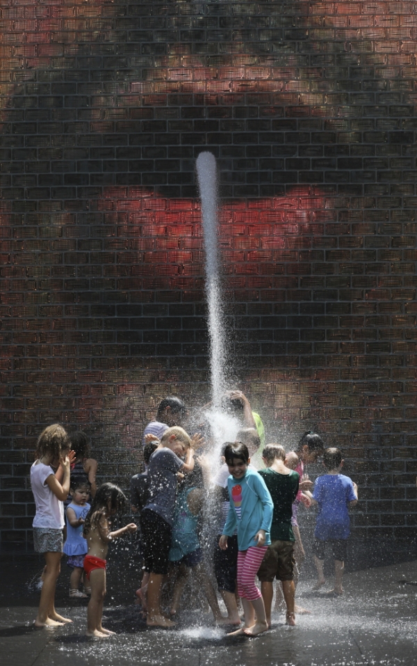20일(현지시간) 미 일리노이주 시카고의 밀레니엄 공원에서 쏟아지는 물줄기에 몰려든 어린이들이 물을 맞으며 더위를 식히고 있다.
