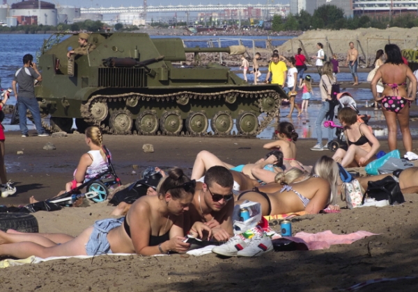1일(현지시간) 러시아 상트페테르부르크 핀란드만에서 제2차 세계대전 재현 행사가 열린 가운데 해변에서 관광객들이 일광욕을 즐기고 있다.  /뉴시스