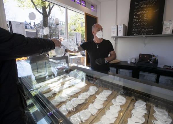 19일(현지시간) 네덜란드 암스테르담의 한 아이스크림 가게에서 이곳 직원이 아이스크림 대신 신종 코로나바이러스 감염증(코로나19) 예방을 위한 FFP2 마스크를 개당 9유로(약 1만2,000원), 3개에 25유로(약 3만3,000원)에 팔면서 손님을 기다리고 있다. /뉴시스