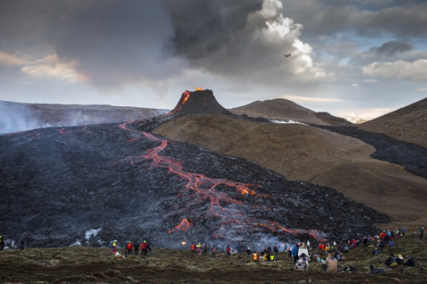23일(현지시간) 아이슬란드 남서부 레이캬네스 반도의 그린다비크에서 관광객들이 파그라달스피아들 화산이 폭발해 흘러내린 용암을 구경하고 있다. 이 화산의 용암 분출이 느리게 진행돼 인근 마을에 위협적으로 여겨지지 않아 이를 보기 위해 최근 수많은 관광객이 몰려들어 관광명소로 주목받고 있다. /뉴시스