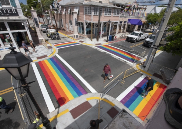 15일(현지시간) 미 플로리다주 키웨스트의 한 교차로에서 키웨스트 공공근로부문 담당자인 폴 캐시디(오른쪽)가 가스 불을 이용해 무지개 깃발 형상을 건널목에 덧입히고 있다. LGBTQ를 상징하는 무지개 건널목의 설치는 키웨스트 듀벌(Duval) 거리 대부분을 재포장하면서 적용됐다.  /뉴시스