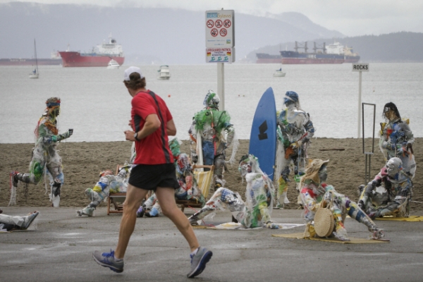 6일(현지시간) 캐나다 브리티시컬럼비아주 밴쿠버의 키칠라노 해변에서 한 남성이 플라스틱 쓰레기로 만든 사람 형상의 조형물들을 바라보며 조깅하고 있다. 예술가 케이틀린 도허티는 플라스틱 오염에 대한 사람들의 경각심을 고취하고 해변 공해 문제를 부각하기 위해 캐나다 해안가에서 수거한 각종 플라스틱을 이용해 '플라스틱 해변 관광객'이라는 이름으로 조형물들을 만들었다. /뉴시스